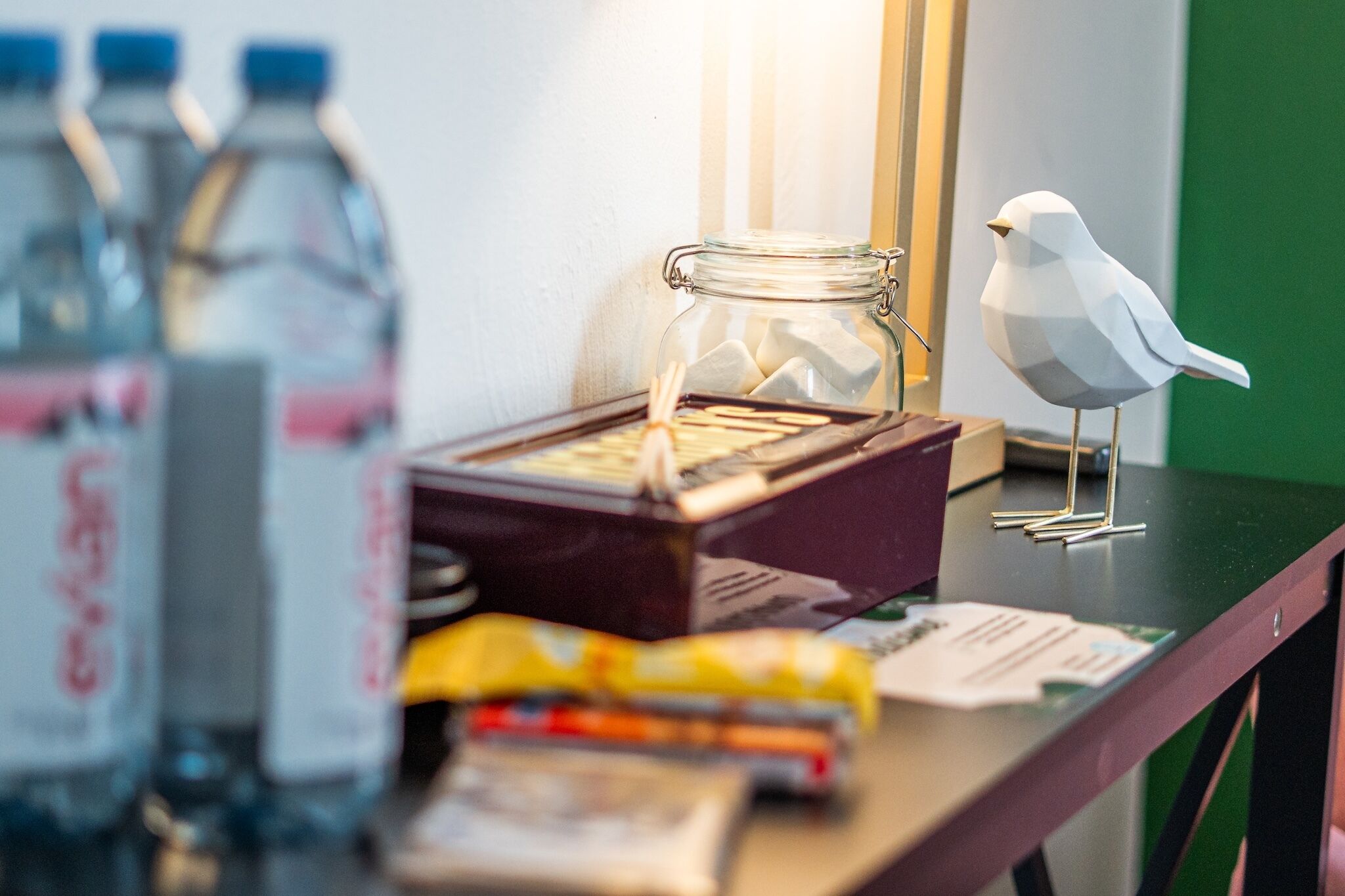 A desk with a glass jar, a white bird figurine, and various items including a box and papers.