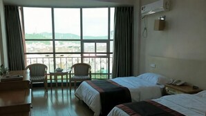 Een hotelkamer met twee bedden, een bureau, stoelen en een groot raam met uitzicht.