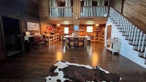 Un interior rústico con una zona central de comedor, una escalera de madera y un tapiz de cuero de vaca.