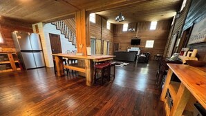 Una cocina amplia con pisos de madera, una isla central y una escalera que conduce a un nivel superior.