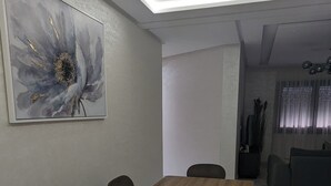 A dining area with a wooden table and black chairs, a large abstract painting on the wall, and a ceiling light fixture. - Fez apartment (Fès)