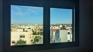 A window with a view of a cityscape, featuring multiple buildings and a clear sky. - Fez apartment (Fès)