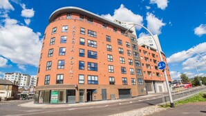 A multi-story building with a curved facade, a sign reading "KATARIA POINT," and a blue pedestrian sign indicating a footpath. - Ilford Tower Apartments (Ilford)