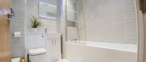 Un baño moderno con inodoro, lavamanos y ducha.