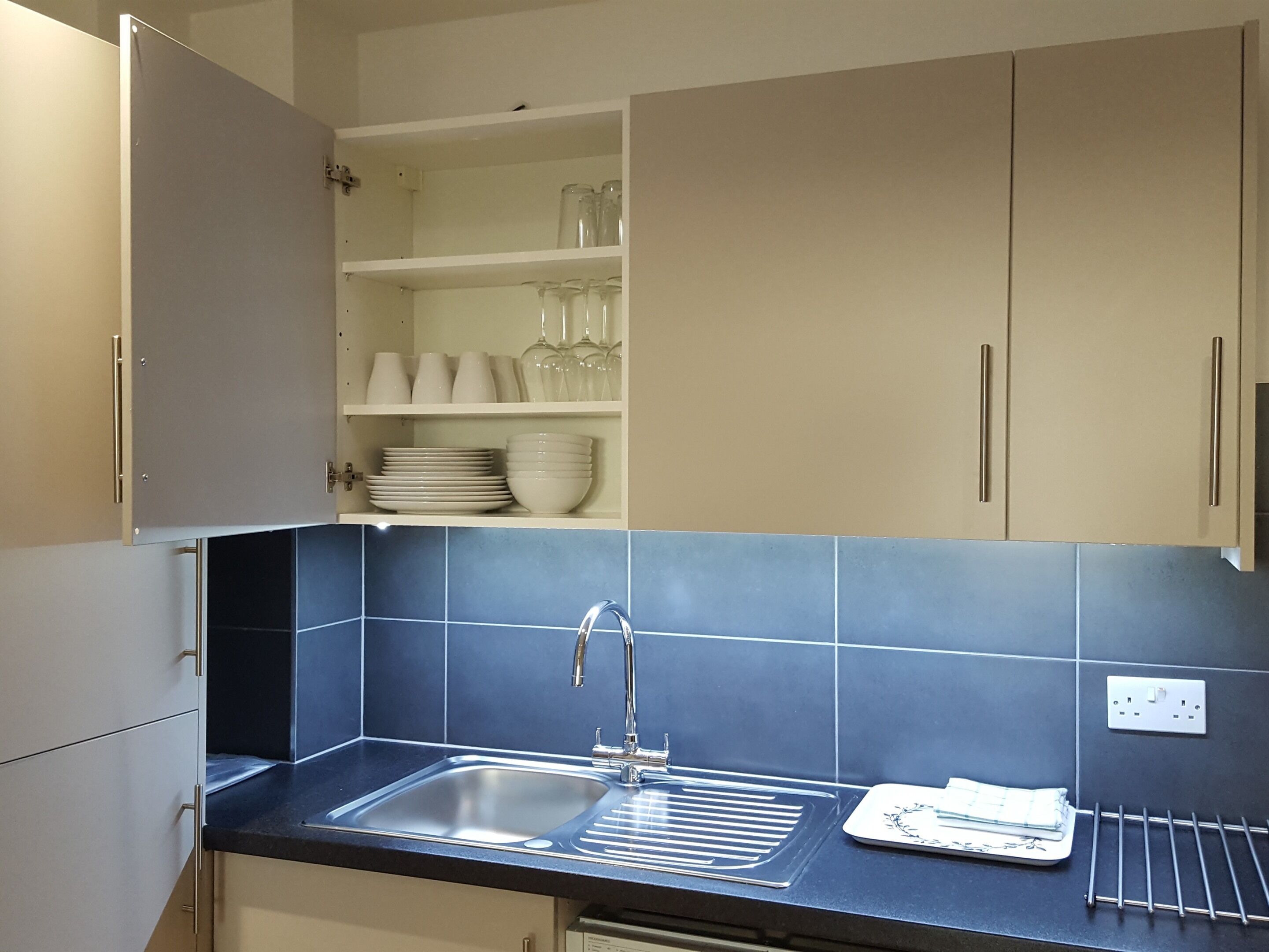 A kitchen with a sink, cabinets, and a tiled backsplash.
