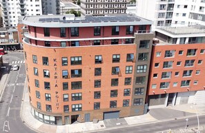 A multi-story building with a curved facade, large windows, and a rooftop with solar panels. - Ilford Tower Apartments (Ilford)