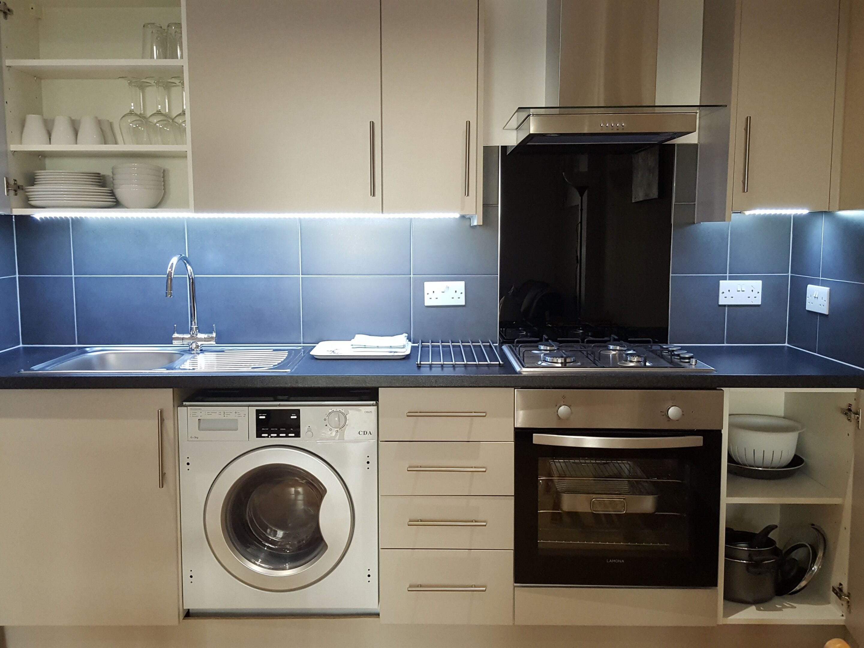 A compact kitchen with a washing machine, oven, and a built-in stove.
