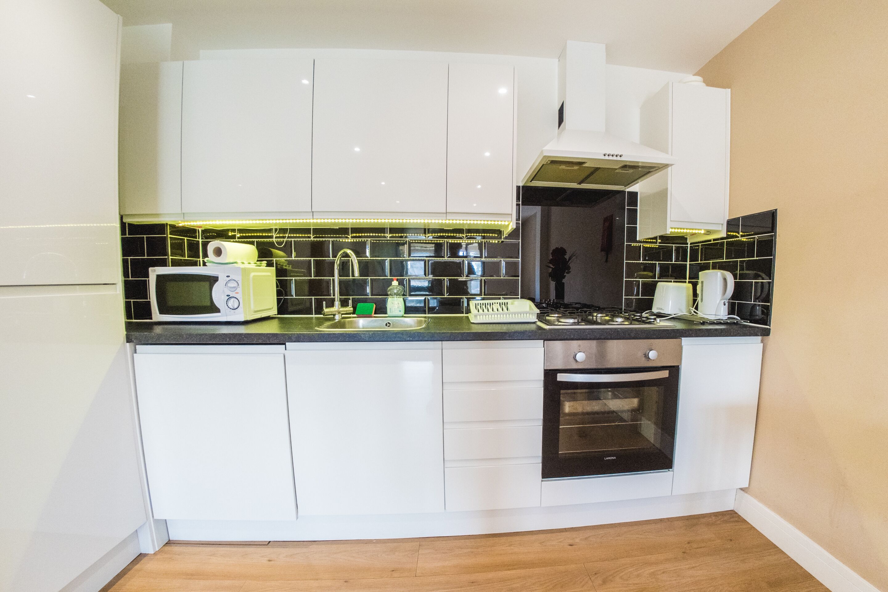 A compact kitchen with white cabinets, a microwave, a stove, and a dishwasher.