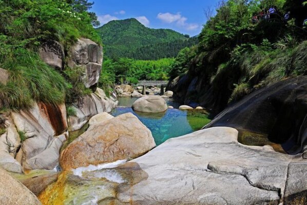 Un paisaje natural con un arroyo cristalino, rocas grandes y un puente.