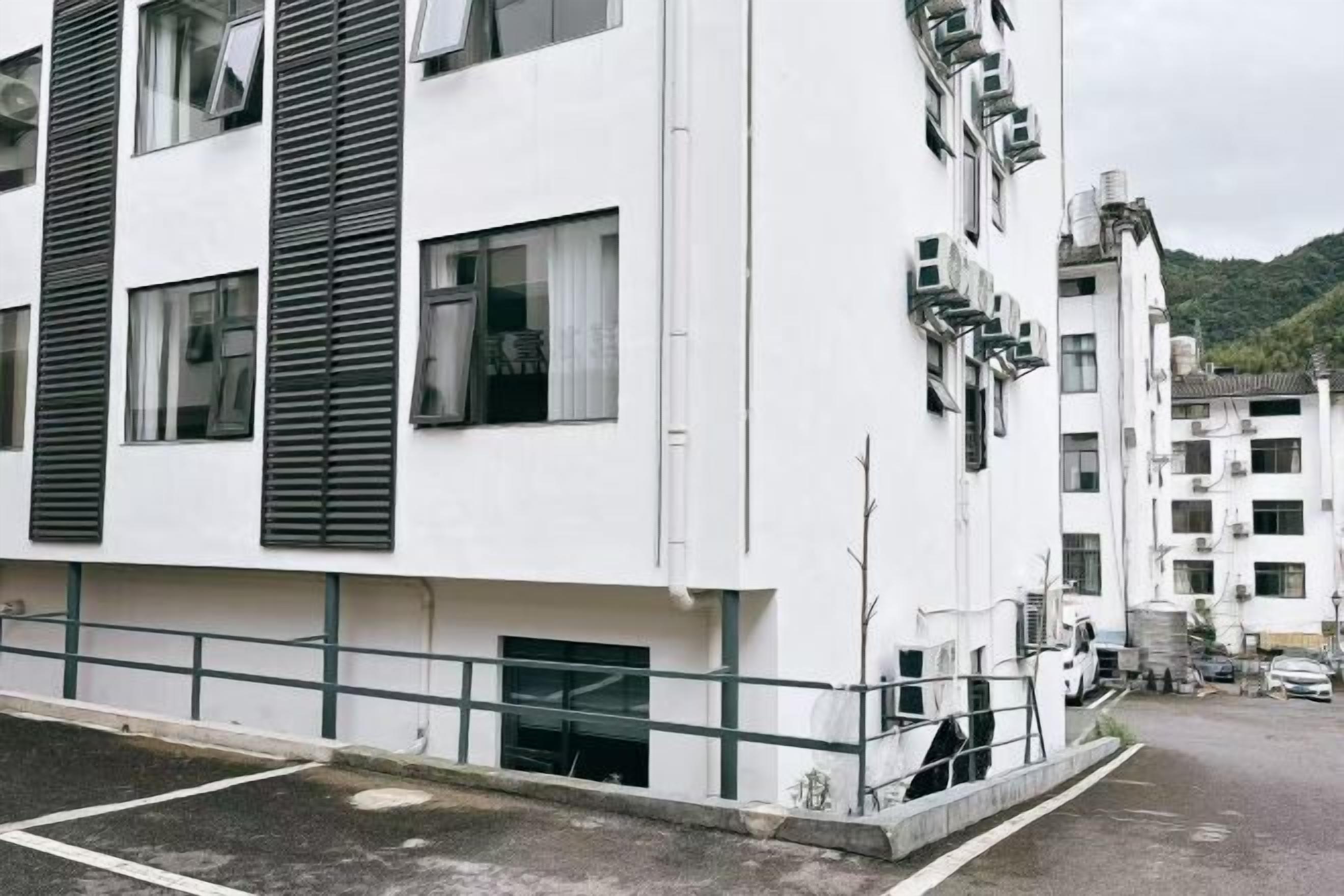 Un edificio de varios pisos con fachada blanca, ventanas grandes y techo plano.