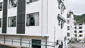 Un immeuble à plusieurs étages, doté d’une façade blanche, de grandes fenêtres et d’un toit plat.