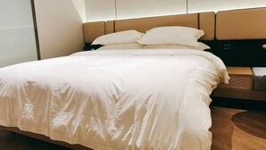 Un lit bien fait, avec une tête de lit, une table de chevet et un panneau de commande fixé au mur.
