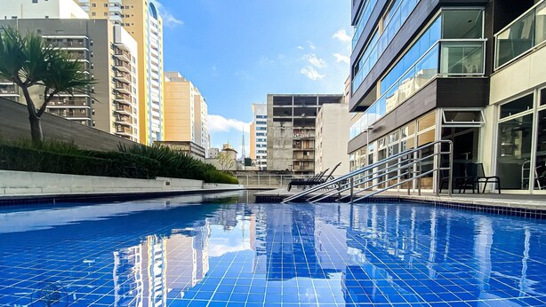 Une piscine aux carreaux bleus, entourée de bâtiments modernes dotés de balcons et de grandes fenêtres.