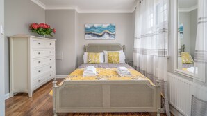 A neatly arranged bedroom with a bed, a dresser, and a painting on the wall. - Elegant 3Bedroom Retreat (London)