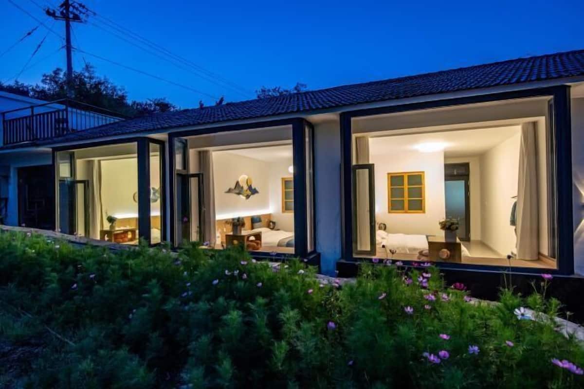 Uma casa moderna com amplas portas de vidro que dão acesso a um quarto e um banheiro.