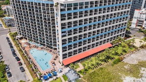 Un grand hôtel à plusieurs étages, doté d’une piscine et d’un bâtiment adjacent au toit rouge.
