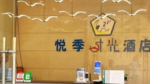 Una recepción de hotel con un cartel que dice "Joyful Hotel" y un código QR sobre el mostrador.