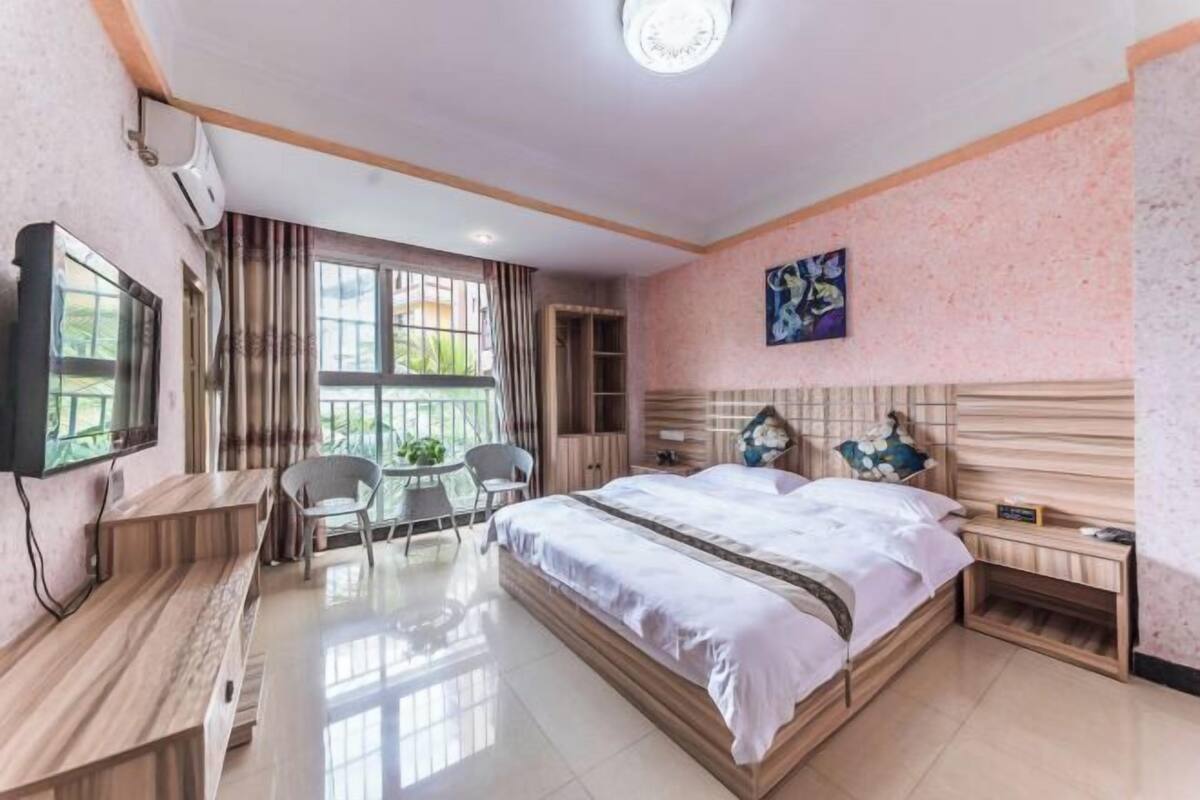 A hotel room with a bed, a desk, a chair, a TV, and a window with curtains.