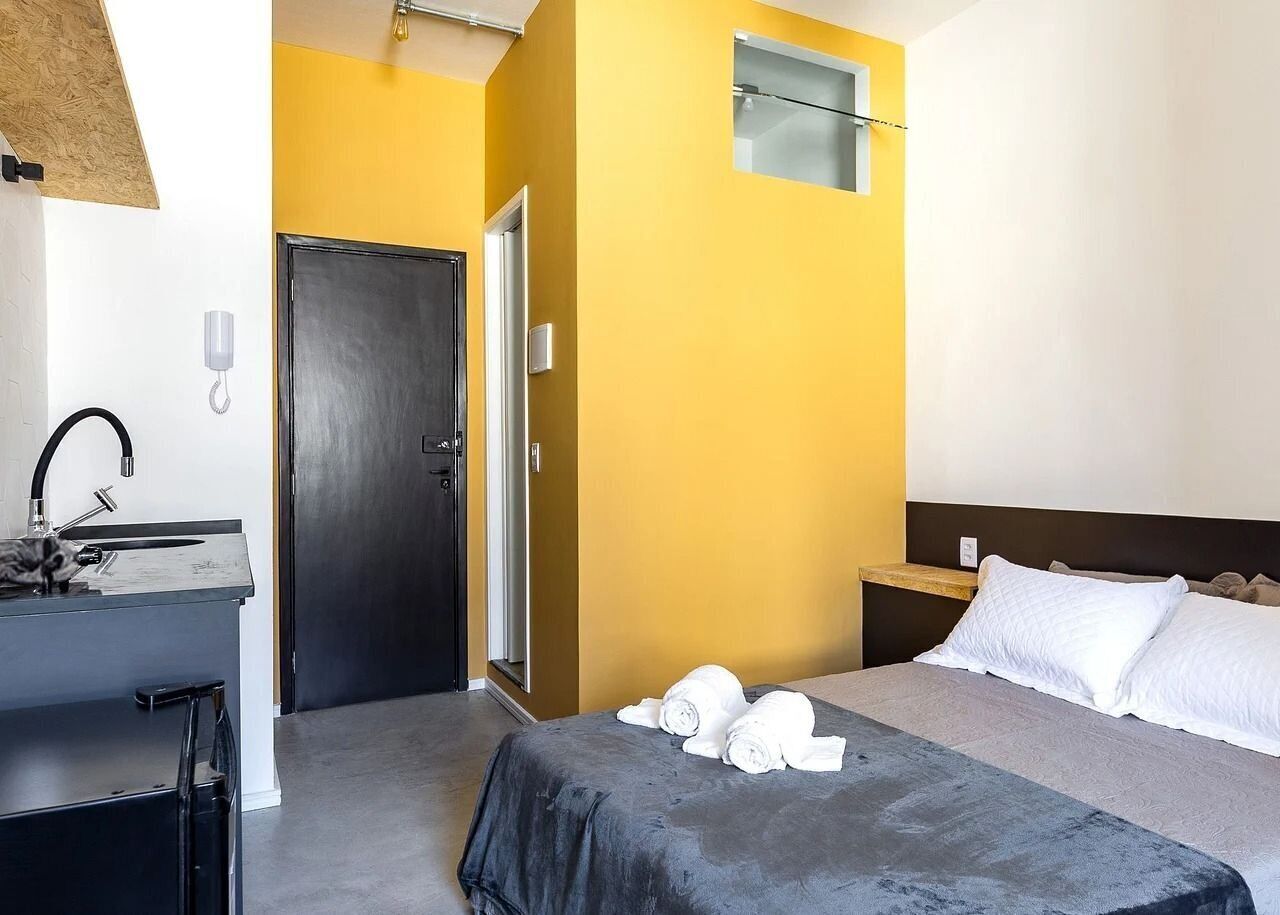 Ein Hotelzimmer mit einem Bett, einem Schreibtisch mit Spüle und einer Tür.