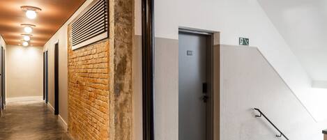 A hallway with a brick wall, a door labeled '101', and a staircase with a handrail.