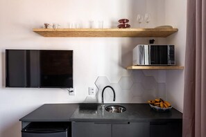 A modern kitchen with a flat-screen TV, a microwave, a sink, and a fruit bowl. - Zest Teodoro (São Paulo)