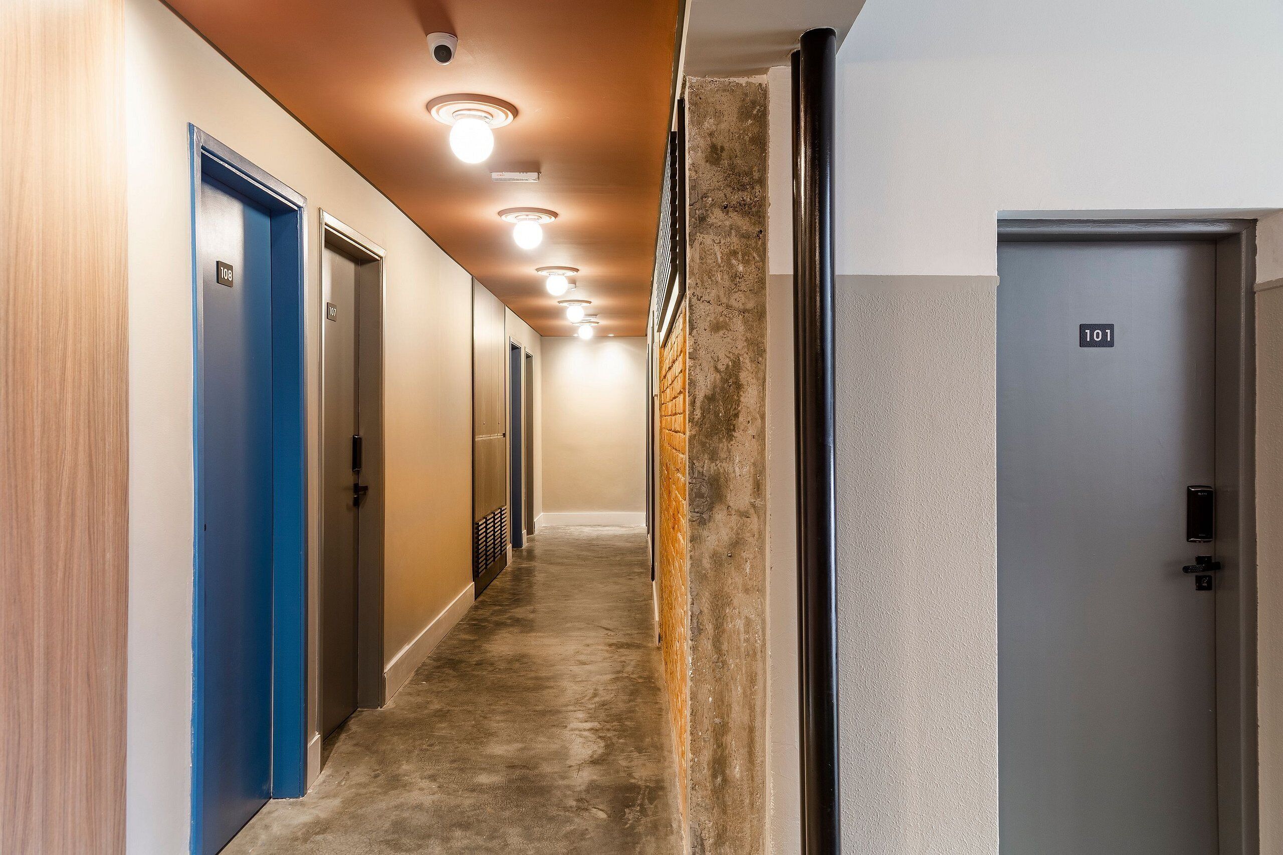 A hallway with doors numbered 101 and 108, a textured wall, and a ceiling with recessed lighting.