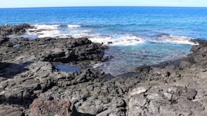 Una costa rocosa con aguas azules y transparentes.
