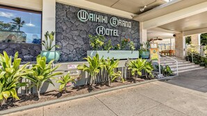L’extérieur du Waikiki Grand Hotel se caractérise par sa façade en pierre, son hall d’accueil et un escalier menant à l’entrée.