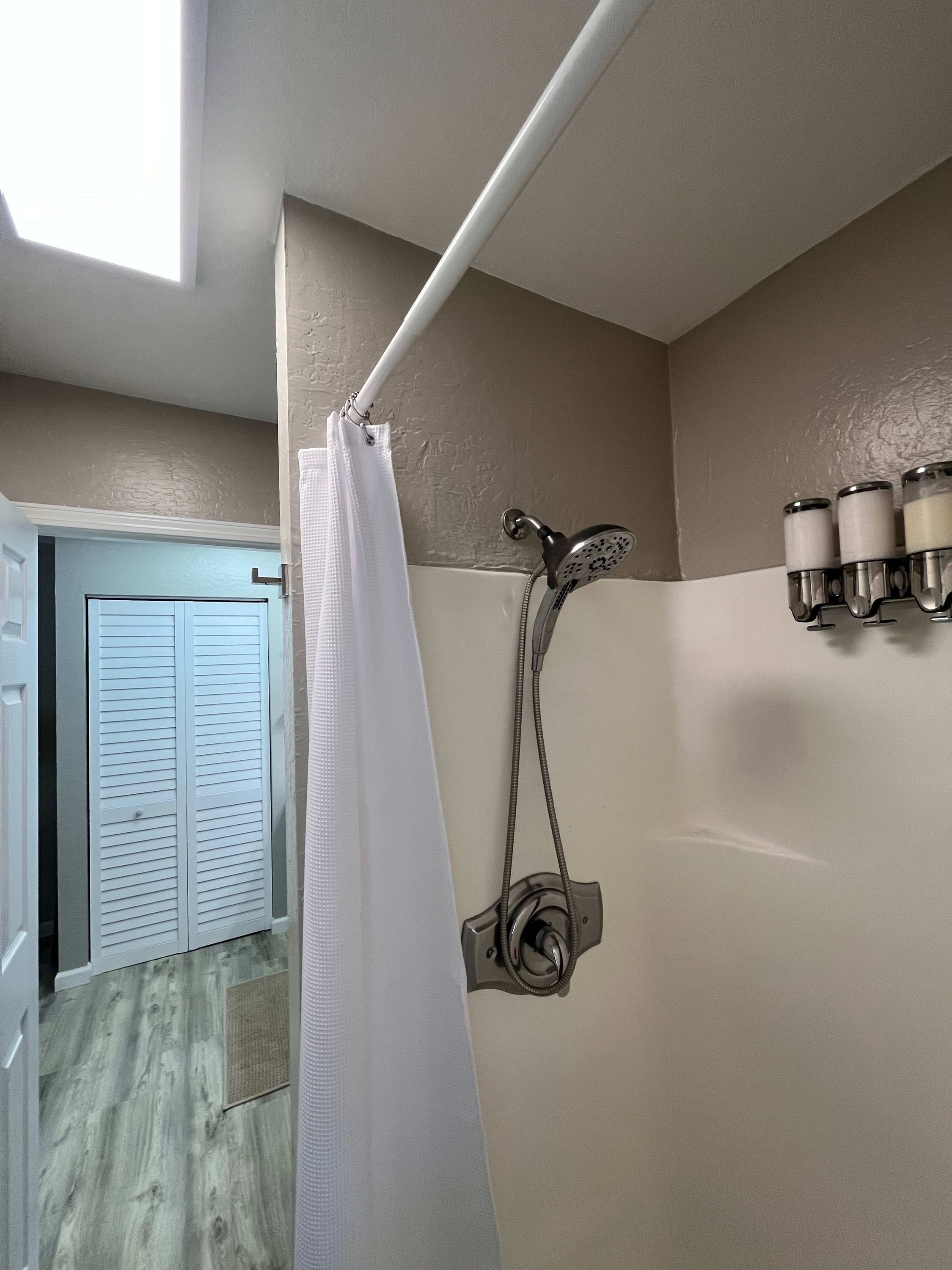 Ein Badezimmer mit Dusche, Handtuchhalter und einer Tür zu einem anderen Raum.