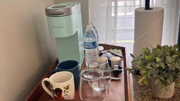 A kitchen counter with a coffee maker, a water bottle, a mug, and a tray.