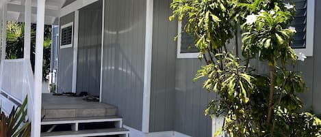 Una casa de dos pisos con un porche cubierto y un árbol pequeño en el jardín delantero.