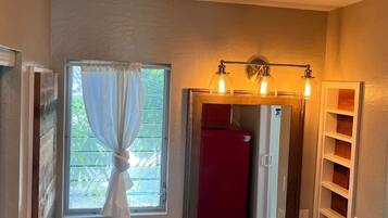A bathroom with a marble countertop, a sink, a mirror with lights, and a window with curtains.