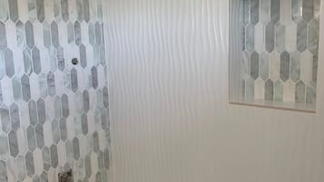 A bathroom with a hexagonal tile pattern on the wall, a white textured wall, and a small window with a similar tile design.