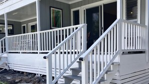 Un bâtiment à deux étages, à l’extérieur blanc, doté d’un porche couvert avec des balustrades blanches et d’un escalier menant à l’entrée.