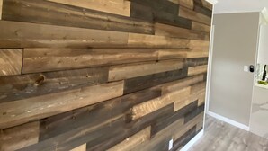 Une pièce dont un mur est recouvert de panneaux en bois et qui possède une porte donnant sur une autre pièce.