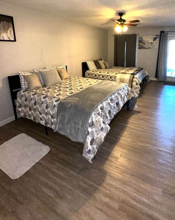 A bedroom with two beds, a ceiling fan, and a large window.