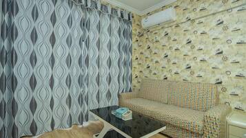 A room with a patterned sofa, a black coffee table, and a patterned wall.