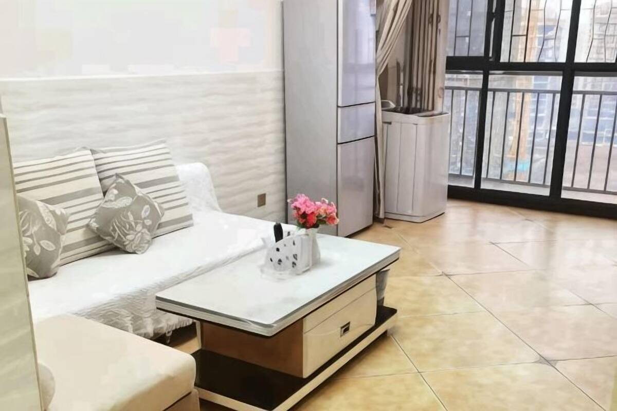 Un salon moderne avec un canapé, une table basse et une vue dégagée grâce à de grandes fenêtres.