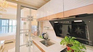 A modern kitchen with a built-in oven, a stainless steel sink, and a glass door separating the kitchen from the dining area. - Shuangshu Apartment Hotel (Changsha Chuangshiji Plaza) (Changsha)