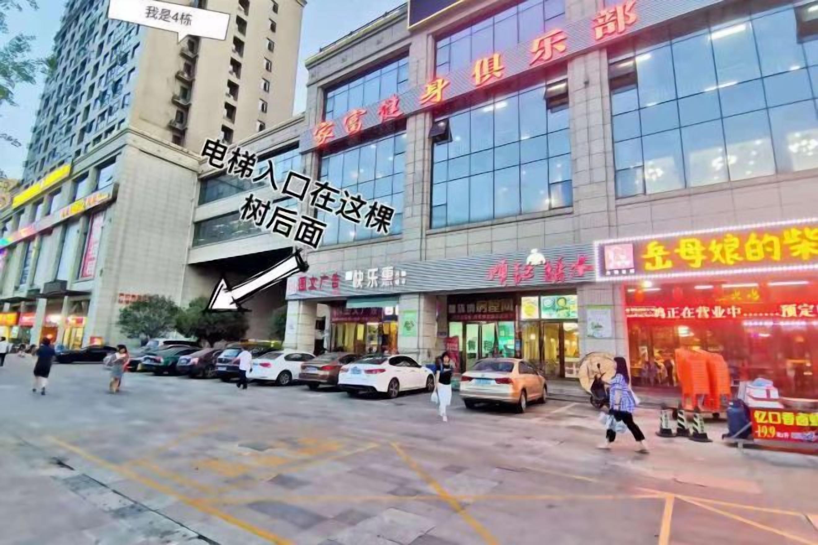 A commercial building with multiple storefronts, a parking area, and a pedestrian walkway.