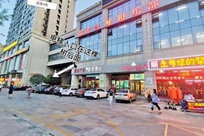 A commercial building with multiple storefronts, a parking area, and a pedestrian walkway.
