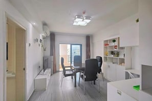 A modern living room with a dining area, a TV, and a bookshelf.