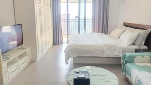 A hotel room with a bed, a TV, a balcony, and a view of the outside. - Shuangshu Apartment Hotel (Changsha Chuangshiji Plaza) (Changsha)