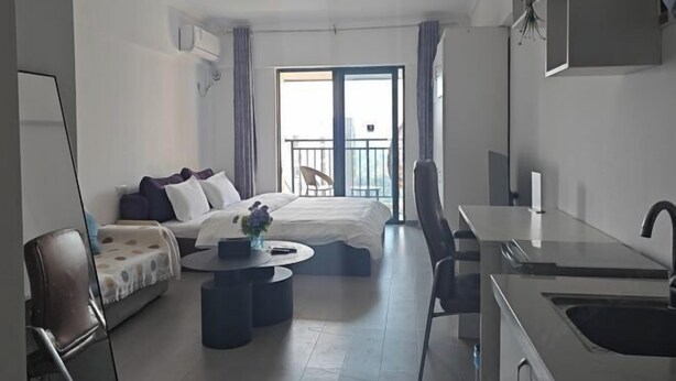 A modern hotel room with a bed, a sofa, a dining table, a kitchen area, and a balcony with a view. - Shuangshu Apartment Hotel (Changsha Chuangshiji Plaza) (Changsha)