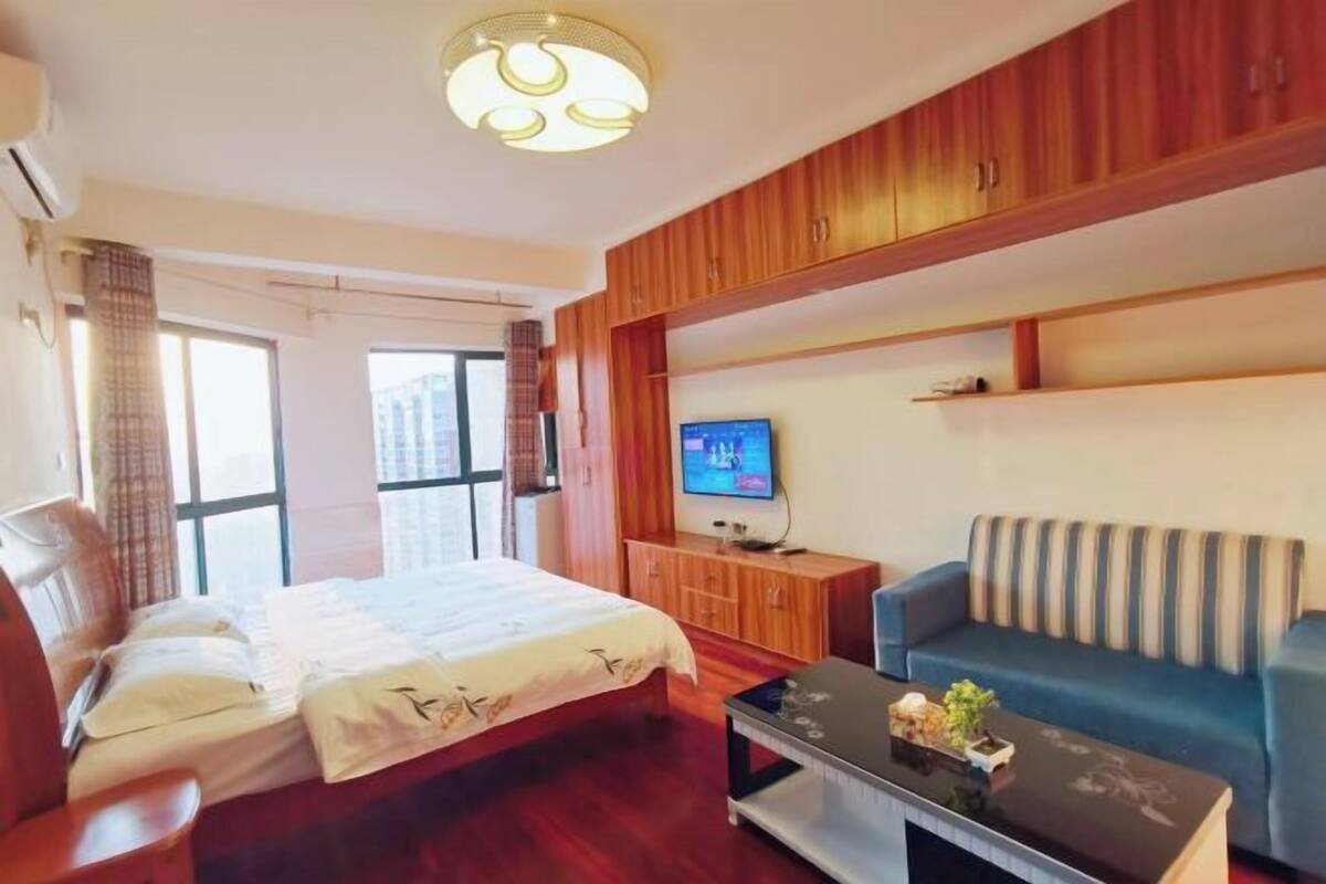 Une chambre d’hôtel avec un lit, une télévision, un canapé et des meubles en bois.