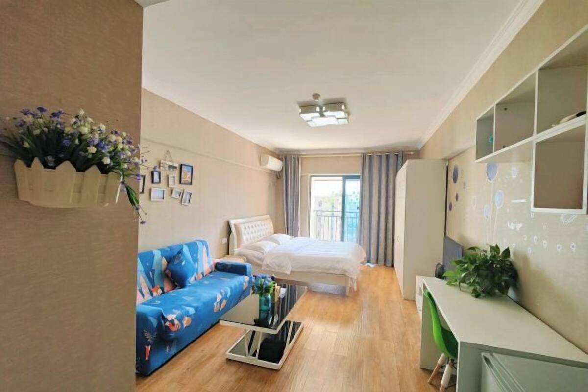 Une pièce de taille modeste comprenant un lit, un canapé, un bureau et un petit balcon.
