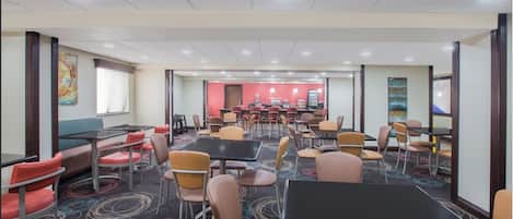 A conference room with tables and chairs, a carpeted floor, and a red accent wall.