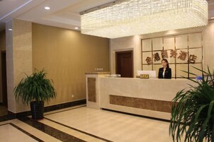A reception area with a reception desk, a large chandelier, and a potted plant.