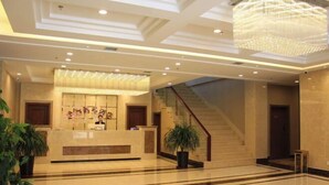 A hotel lobby with a reception desk, a staircase, and a chandelier. - Panjin Jingang Business Hotel (Panjin)