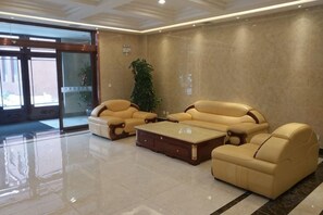 A lobby with a seating area, a large plant, and a glass door entrance. - Panjin Jingang Business Hotel (Panjin)